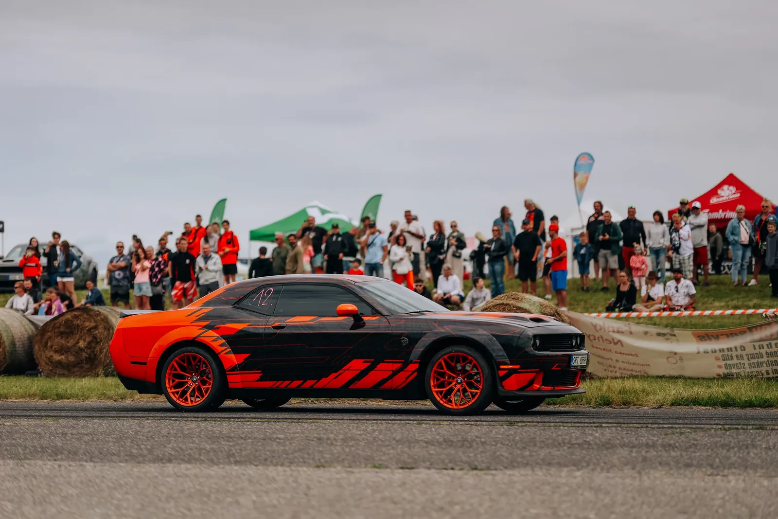 Dodge Challenger s oranžovo-černým polepem projíždí kolem diváků na US Cars Fest